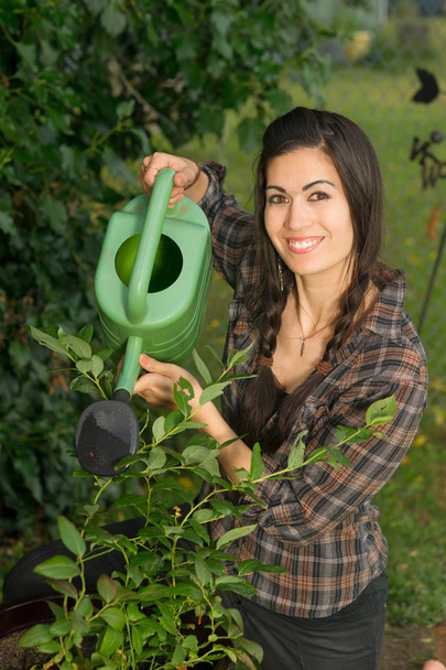 Portret vrouw drenken Plant zaailing buiten kweken van voedsel - Foto, afbeelding
