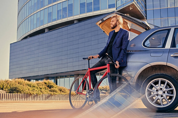 Бородач держит неподвижный велосипед
 - Фото, изображение