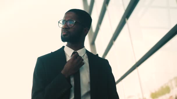 Portrait of confident attractive african american businessman standing outdoors near office center bulding windows. Close up - Felvétel, videó