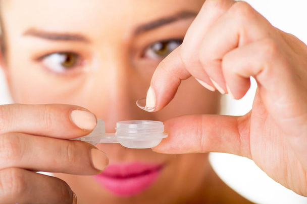 Young woman holding contact lenses cases and lens in front of her face - Photo, Image