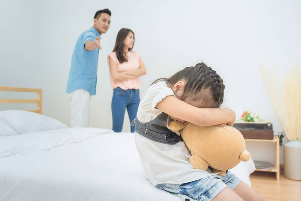 Aziatische little girl verdriet terwijl ouders ruzie in slaapkamer. - Foto, afbeelding