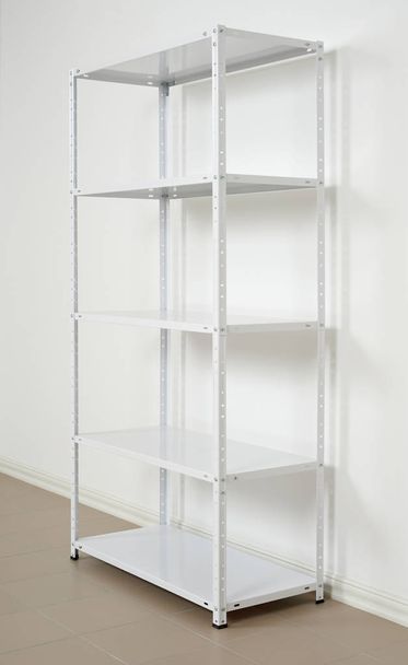 white metal rack near the wall, empty shelves - Photo, Image