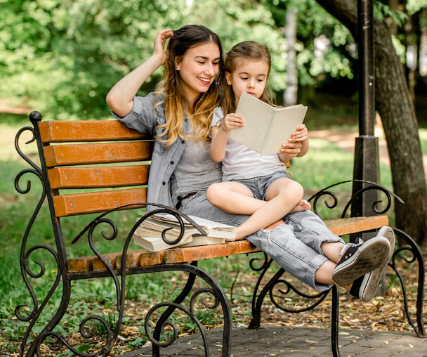 Mamma e figlia su una panchina a leggere un libro
 - Foto, immagini