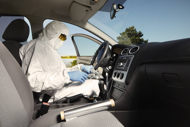 Criminologist technician collecting odor traces from driving wheel - Fotó, kép