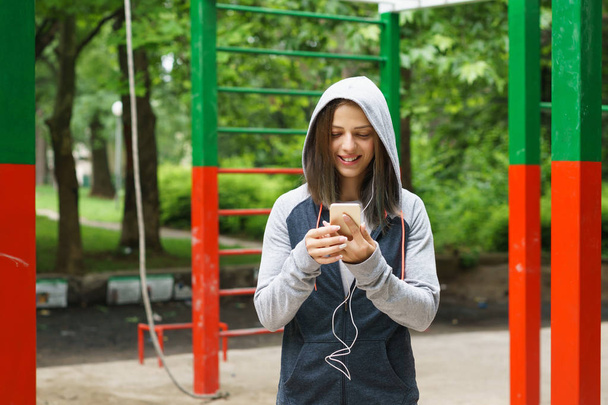 Молода фітнес-леді смс на смартфоні на відкритому повітрі
 - Фото, зображення