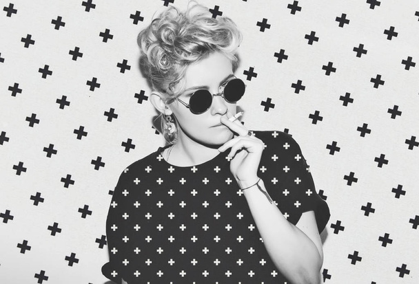 Contrast pattern stylish fashion sexy blonde bad girl in a black t-shirt and rock sunglasses. Dangerous rocky emotional woman. white toned. background, not isolated - Foto, imagen