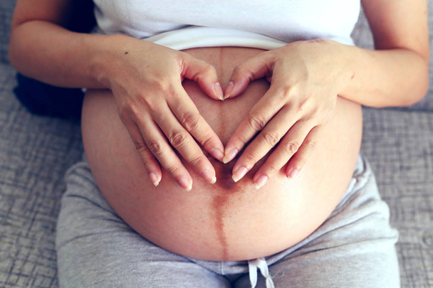 beautiful woman pregnant hand heart signals for baby love - Valokuva, kuva