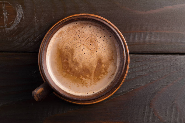 Гарячий шоколад або какао напій у глиняній чашці, на темно-коричневому дерев'яному столі, вид зверху
. - Фото, зображення