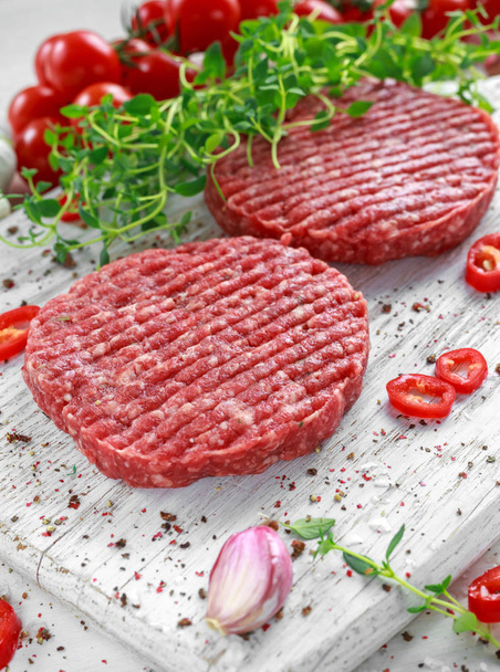 Carne fresca cruda, empanadas redondas para hacer hamburguesa casera en tablero blanco de madera
 - Foto, Imagen