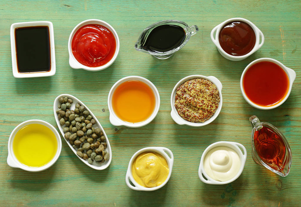 Различные типы соусов и масел в мисках, вид сверху
 - Фото, изображение