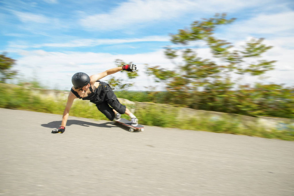 Young man in helmet is going to slide, slide with sparks on a longboard on the asphalt - Foto, afbeelding
