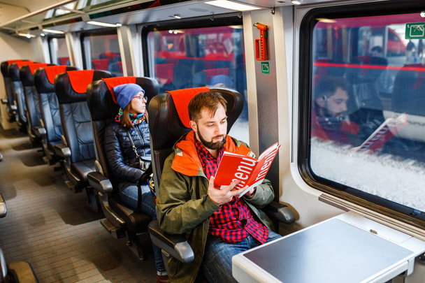 Egy szép szakállas ember utazik a vonaton, és beolvassa a menü - Fotó, kép