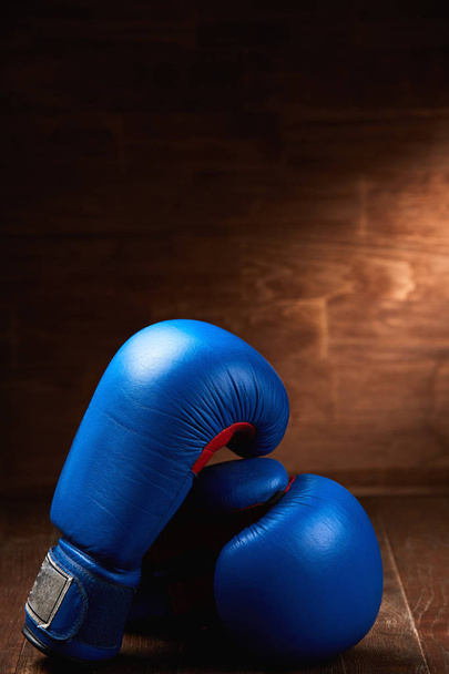 Pair of the two red boxing gloves lie on wooden table against wooden background. - Foto, Imagem