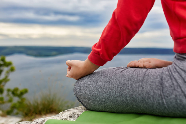 Крупный план женщины, сидящей в позе лотоса и медитирующей на скале
. - Фото, изображение