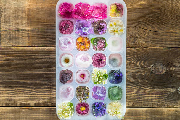 Tablett mit gefrorenen Blumen in Eiswürfeln - Foto, Bild