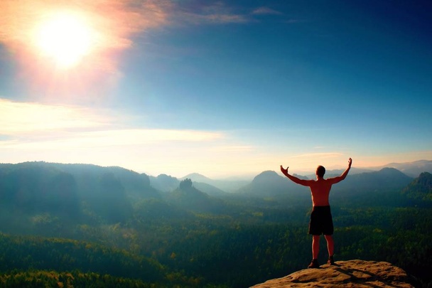 Arrampicante in pantaloni neri. Gesto di trionfo. Corpo nudo uomo sulla cima della roccia arenaria nel parco nazionale Sassonia Svizzera
 - Foto, immagini