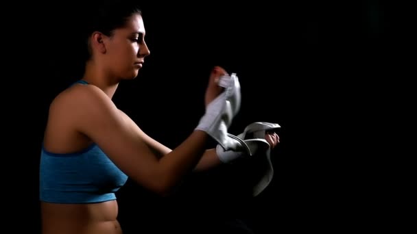 Молодая женщина, занимающаяся боксом ногами тренировки надевая перчатки на черном фоне, замедленная съемка
 - Кадры, видео