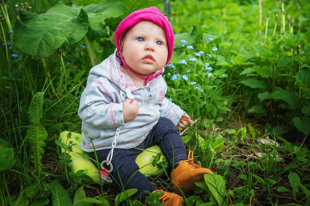 Baby girl sitting in tall green grass under the mug. - Photo, Image