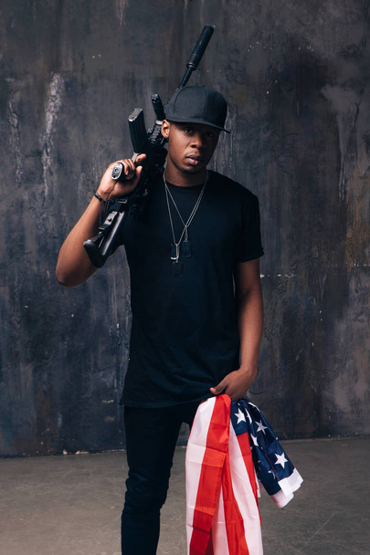 Homem negro armado com bandeira e arma
 - Foto, Imagem