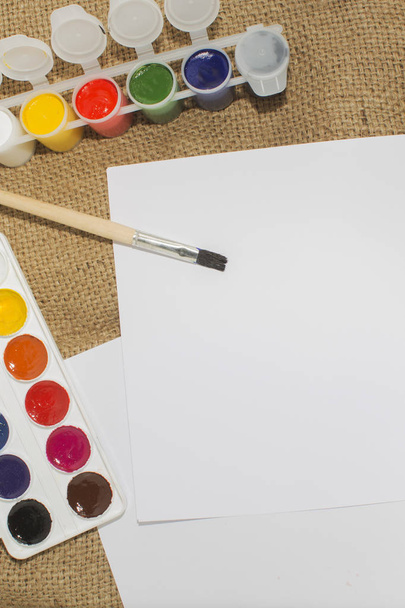 Zestaw akwarela farby, pędzle do malowania i puste białego papieru kartce sketchbook. - Zdjęcie, obraz