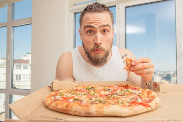Pizza. A guy with a beard eats pizza - Foto, afbeelding