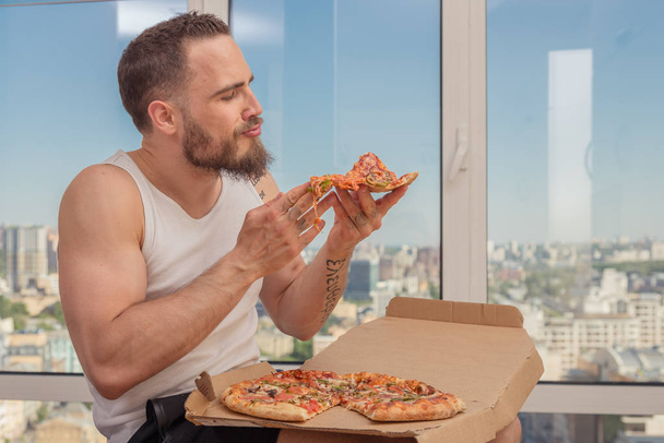 Pizza. A guy with a beard eats pizza - Foto, afbeelding