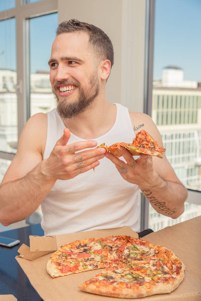 Pizza. A guy with a beard eats pizza - Zdjęcie, obraz