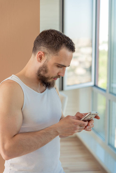 A guy with a beard looks at the phone - Фото, зображення