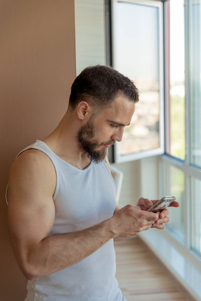 A guy with a beard looks at the phone - Foto, imagen