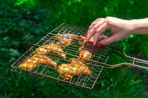 Su una griglia grattugiano pezzi di pollo fritti su uno sfondo di verdi lavati
 - Foto, immagini
