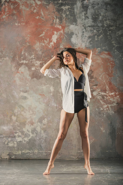 Girl dancing on a gray wall background - Foto, afbeelding