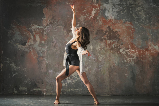 Girl dancing on a gray wall background - 写真・画像