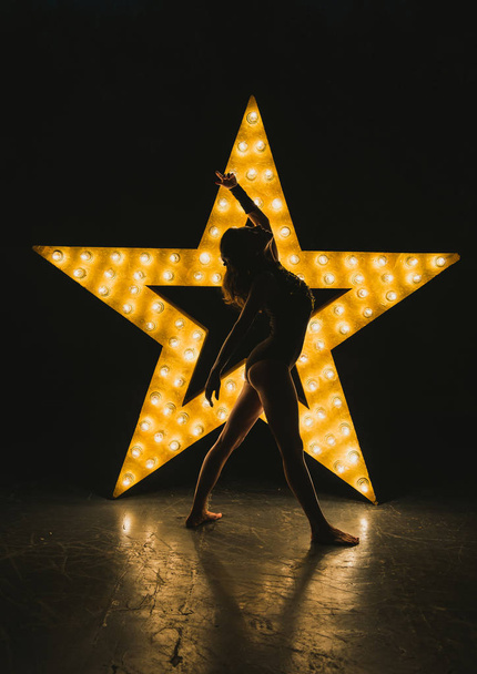 The girl is dancing against the backdrop of a glowing star - Fotoğraf, Görsel