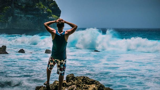 Man Provoke Ocean Waves on Tembeling Coastline at Nusa Penida island, Bali Indonesia - Φωτογραφία, εικόνα