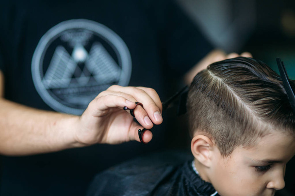 Little Boy Getting Haircut By Barber While Sitting In Chair At Barbershop. - Photo, Image