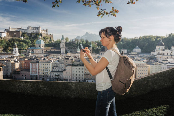 Austria. Salzburgo. Chica joven turista tomando fotos en el teléfono móvil
 - Foto, Imagen