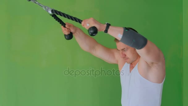 Athletic young man working out on fitness exercise equipment at gym - Footage, Video