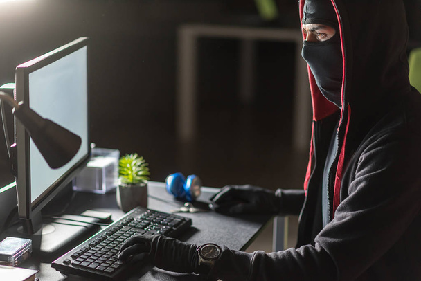 Composed hacker stealing data at desk - Фото, изображение