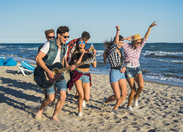 Вечірка на пляжі з гітарою. Друзі танцюють разом на пляжі
 - Фото, зображення