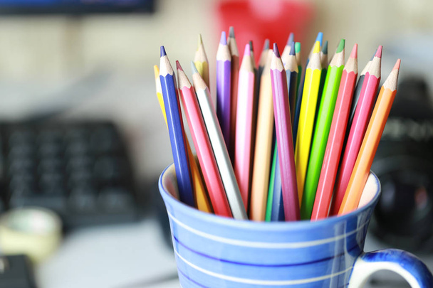 Crayon colorido na xícara azul na mesa de trabalho
. - Foto, Imagem