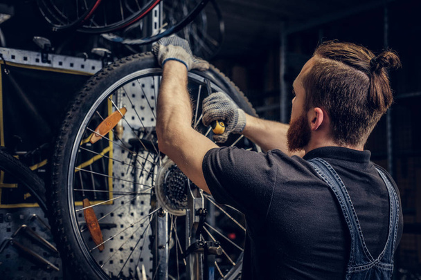 Bearded mechanic repairing bicycle  - Foto, Imagen