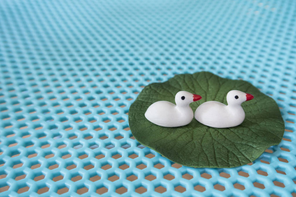 Patos blancos de cerámica sobre hoja verde loto
. - Foto, Imagen