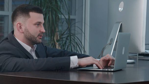Attractive caucasian businessman using laptop, while talking with partner at workplace - Foto, immagini