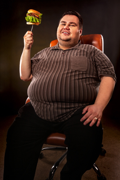 Hombre gordo comiendo hamburguesa de comida rápida. Desayuno para personas con sobrepeso
. - Foto, Imagen