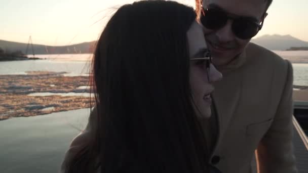 Szerető pár csók, a beállítás nap lassított stock footage videóinak sugaraiban Pier - Felvétel, videó