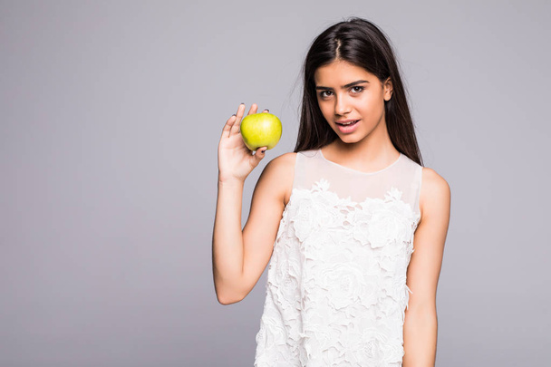 Closeup portrait of lovely young brunette woman biting juicy fresh delicious apple against gray background. - 写真・画像