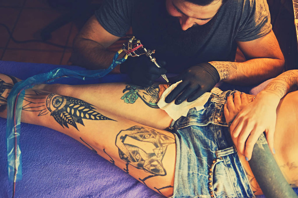 Szakállas tetováló művész teszi a tetoválás - Fotó, kép
