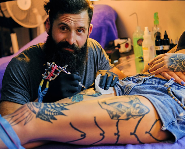 Γενειοφόρος τατουάζ καλλιτέχνης κάνει μια δερματοστιξία - Φωτογραφία, εικόνα