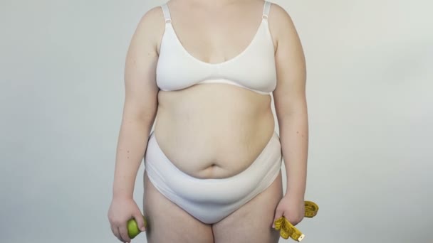 Толстая женщина показывает яблоко и ленту перед камерой, здоровый образ жизни, диета
 - Кадры, видео