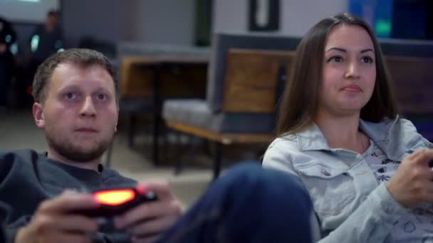 Young couple playing video game at home. Man explayning how to play and use the game controller. Xbox and Playstation. Wireless game controler. Slowmotion shot - Záběry, video